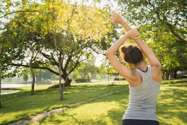 公園の緑の中でストレッチをする女性の後ろ姿